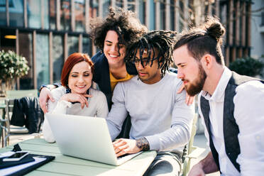 Eine Gruppe junger Geschäftsleute, die draußen im Hof einen Laptop benutzen, Konzept für ein Start-up. - HPIF26191