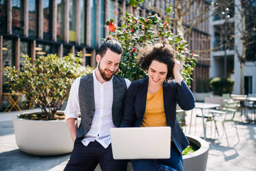 Young businesspeople with laptop outdoors in courtyard, working. Start-up concept. - HPIF26193