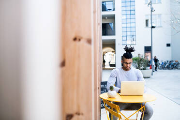 Young businessman with laptop outdoors in courtyard, talking. Start-up concept. Copy space. - HPIF26199