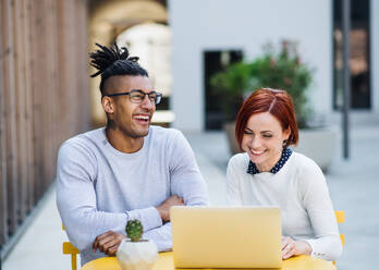 Young businesspeople with laptop outdoors in courtyard, talking. Start-up concept. - HPIF26203