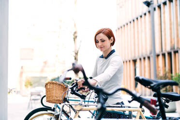 Ein Porträt einer jungen Geschäftsfrau mit Fahrrad, die im Freien steht. - HPIF26210