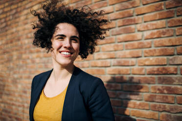 A happy young business woman standing outdoors, brick wall in the background. Start-up concept. - HPIF26221