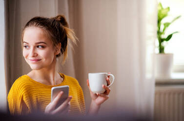 Eine junge Studentin mit Kaffee und Smartphone, die sich ausruht. Kopierraum. - HPIF26245