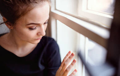 Nahaufnahme einer jungen, traurigen und frustrierten Studentin, die auf der Fensterbank sitzt. - HPIF26273