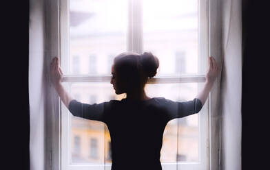 A rear view of young sad female student standing by window. - HPIF26275