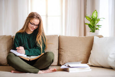 Eine glückliche junge Studentin sitzt auf dem Sofa und lernt. Kopierraum. - HPIF26296
