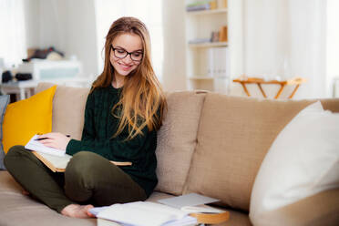 Eine glückliche junge Studentin sitzt auf dem Sofa und lernt. Kopierraum. - HPIF26299