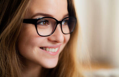 Ein Nahaufnahme-Porträt einer glücklichen jungen Studentin, die in einem Haus steht. - HPIF26301