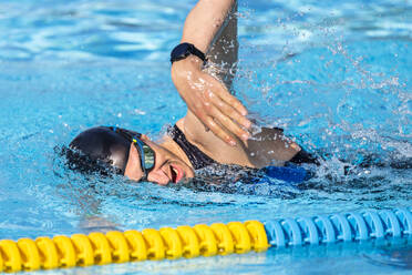 Triathlet schwimmt in der Nähe der Bahnmarkierung im Schwimmbecken - STSF03707