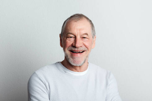 Porträt eines fröhlichen älteren Mannes mit Bart und Schnurrbart in einem Studio, der in die Kamera schaut. - HPIF26331