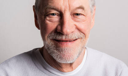 Porträt eines glücklichen älteren Mannes mit Bart und Schnurrbart in einem Studio, der in die Kamera schaut. - HPIF26335