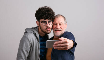 Generationenfreundschaft durch Technologie: Vater und Sohn halten einen Moment mit einem Selfie in einem Studio fest - HPIF26343