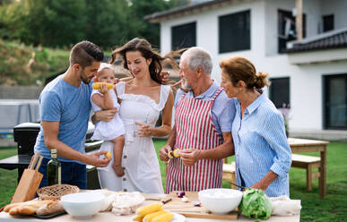 Frontalaufnahme einer Mehrgenerationenfamilie im Freien beim Grillen im Garten. - HPIF26410