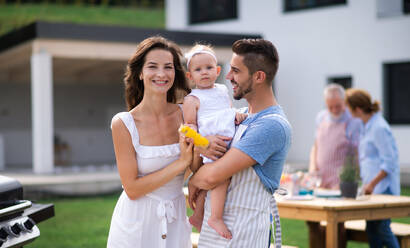 Porträt einer glücklichen Familie mit Baby im Freien auf dem Gartengrill, Grillen. - HPIF26420