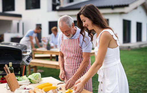 Porträt einer Mehrgenerationen-Familie, die im Garten grillt und sich unterhält. - HPIF26427