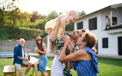 A portrait of multigeneration family outdoors on garden barbecue. - HPIF26442