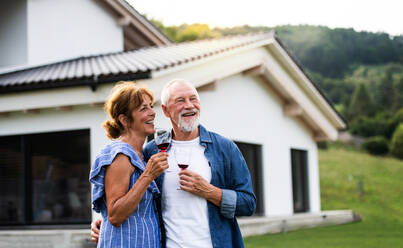 Porträt eines älteren Paares mit Wein im Freien im Hinterhof. Raum kopieren. - HPIF26459