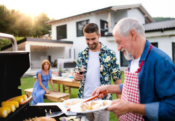 Porträt einer Mehrgenerationen-Familie im Freien beim Grillen im Garten. - HPIF26460