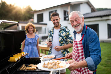 Porträt einer Mehrgenerationen-Familie im Freien beim Grillen im Garten. - HPIF26462