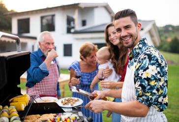 Porträt einer Mehrgenerationen-Familie, die im Garten grillt und sich unterhält. - HPIF26472