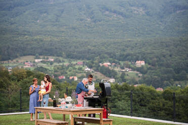 Mehrgenerationenfamilie mit Wein im Freien beim Grillen, Grillen und Reden. - HPIF26473