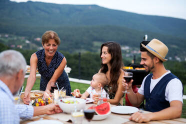 Porträt einer Mehrgenerationenfamilie, die an einem Tisch im Freien sitzt und isst. - HPIF26476