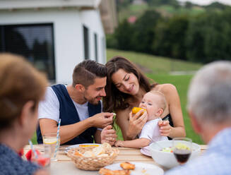 Porträt einer Mehrgenerationenfamilie, die an einem Tisch im Freien sitzt und isst. - HPIF26486