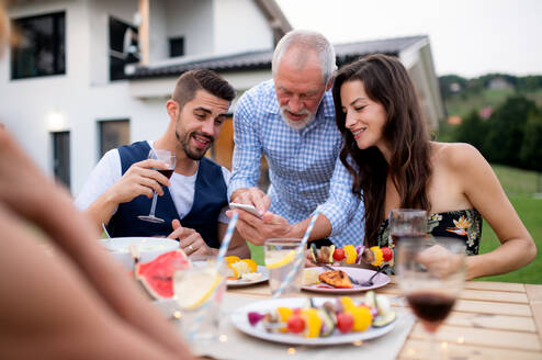 Ein Porträt von Menschen im Freien auf Familiengarten Grill, mit Smartphone. - HPIF26492