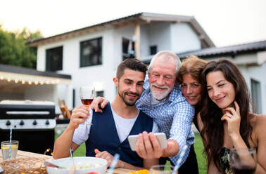 Portrait of people outdoors on family garden barbecue, taking selfie with smartphone. - HPIF26495