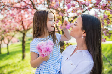 Eine junge Mutter hält ihre kleine Tochter draußen in der Natur im Frühling. - HPIF26502