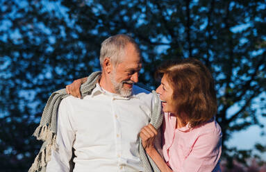 Front view of beautiful senior couple in love outside in spring nature at dusk, talking. - HPIF26573
