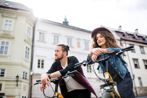 Junges Touristenpaar reist mit Elektrorollern in einer kleinen Stadt, Besichtigung. - HPIF26585