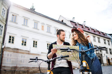 Junges Touristenpaar mit Landkarte und Motorroller in einer kleinen Stadt, Besichtigung von Sehenswürdigkeiten. - HPIF26586