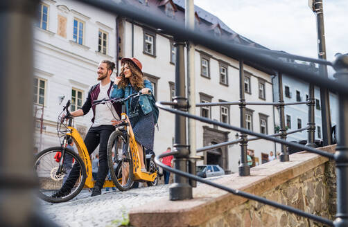 Junges Touristenpaar reist mit Elektrorollern in einer kleinen Stadt, Besichtigung. - HPIF26590