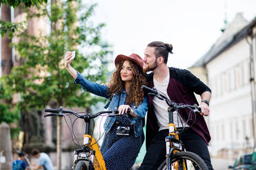 Ein junges Paar erkundet die Stadt auf Elektrorollern und hält die Erinnerungen mit einem Selfie auf dem Smartphone fest - HPIF26602