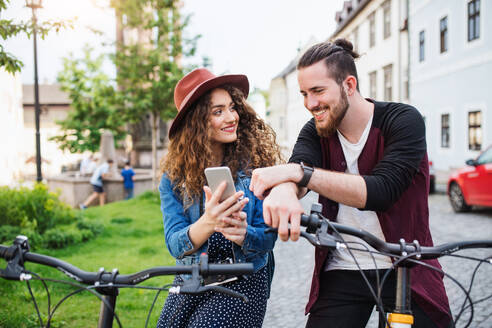 Junges Touristenpaar auf Reisen mit Smartphone und Elektroroller in einer Kleinstadt, Sightseeing. - HPIF26603