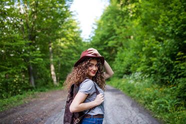 Rückansicht einer jungen Touristin mit Rucksack, die in der Natur spazieren geht, mit Blick zurück. - HPIF26613