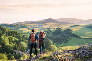 Rückansicht eines jungen Touristenpaares, das mit Rucksäcken in der Natur wandert und sich ausruht. - HPIF26643