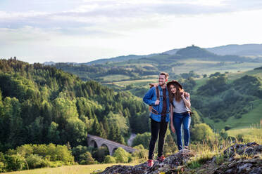 A young tourist couple travellers with backpacks hiking in nature, resting. - HPIF26646