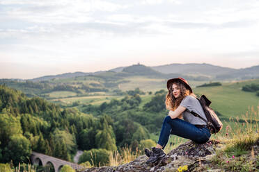 Eine junge Touristin mit Rucksack in der Natur sitzend, Raum kopieren. - HPIF26649