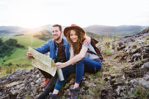 Ein junges Touristenpaar, das mit Rucksäcken in der Natur wandert und eine Karte benutzt. - HPIF26653
