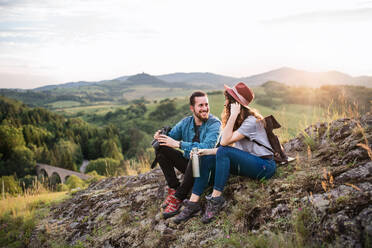 Young tourist couple travellers with binoculars hiking in nature, sitting and resting. - HPIF26654