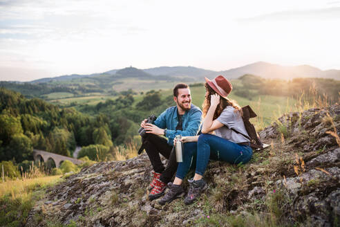 Junges Touristenpaar mit Fernglas beim Wandern in der Natur, sitzend und rastend. - HPIF26654