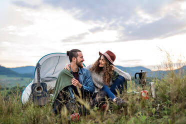 Ein junges Touristenpaar mit Zeltunterkunft sitzt in der Natur und ruht sich aus. - HPIF26667