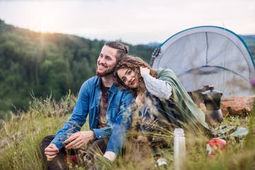 Ein junges Touristenpaar mit Zeltunterkunft sitzt in der Natur und ruht sich aus. - HPIF26671