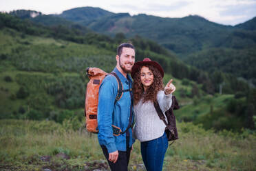Ein junges Touristenpaar, das mit Rucksäcken in der Natur wandert und sich unterhält. - HPIF26681