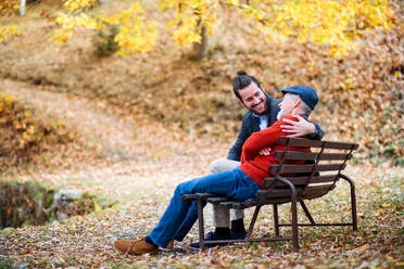Senior father and his young son sitting on bench by lake in nature, talking. - HPIF26693