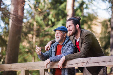 Ein älterer Vater und sein Sohn auf einem Spaziergang in der Natur, stehend und im Gespräch. - HPIF26700