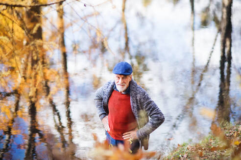 Hoher Blickwinkel auf einen einsamen älteren Mann, der am See in der Natur steht und in die Kamera schaut. - HPIF26709