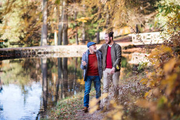 Ein älterer Vater und sein kleiner Sohn gehen in der Natur spazieren und unterhalten sich. - HPIF26711